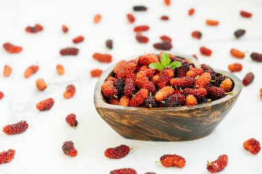 Kırmızı ve siyah dut meyve kase beyaz taş zemin üzerine