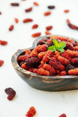 Kırmızı ve siyah dut meyve kase beyaz taş zemin üzerine