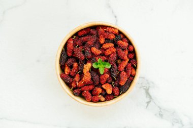 Kırmızı ve siyah dut meyve kase beyaz taş zemin üzerine