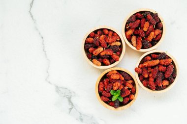 Kırmızı ve siyah dut meyve kase beyaz taş zemin üzerine