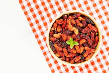 Kırmızı ve siyah dut meyve kase beyaz taş zemin üzerine