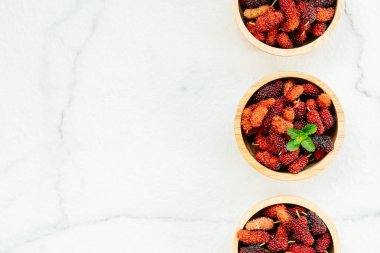 Kırmızı ve siyah dut meyve kase beyaz taş zemin üzerine