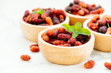 Kırmızı ve siyah dut meyve kase beyaz taş zemin üzerine