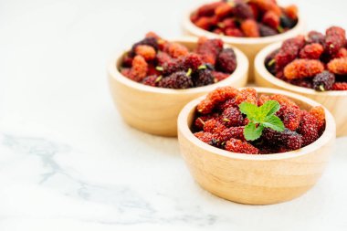 Kırmızı ve siyah dut meyve kase beyaz taş zemin üzerine