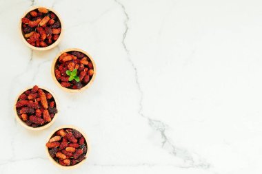 Kırmızı ve siyah dut meyve kase beyaz taş zemin üzerine