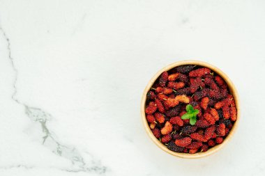 Kırmızı ve siyah dut meyve kase beyaz taş zemin üzerine