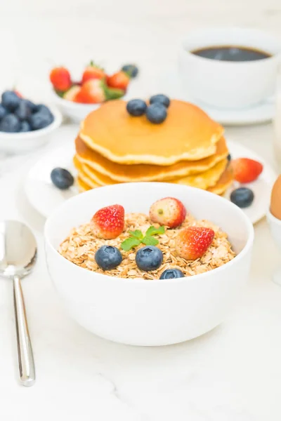 Healthy Breakfast set with Pancake and Granola with blueberry and strawberry and black coffee , Milk and Orange juice on white stone table background