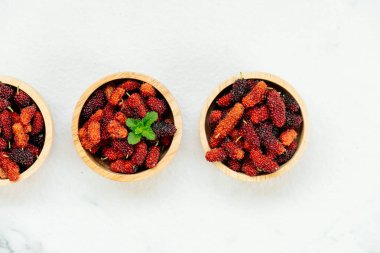 Kırmızı ve siyah dut meyve kase beyaz taş zemin üzerine
