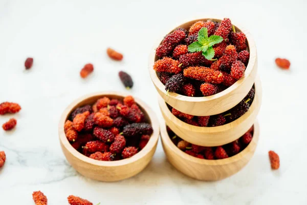 Kırmızı ve siyah dut meyve kase beyaz taş zemin üzerine