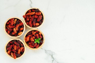 Kırmızı ve siyah dut meyve kase beyaz taş zemin üzerine
