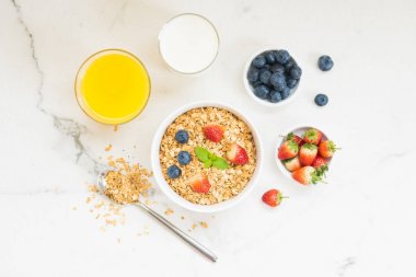 Sağlıklı kahvaltı Granola yaban mersini ve çilek ve siyah kahve, süt ve portakal suyu ile beyaz taş tablo arka planı ayarla