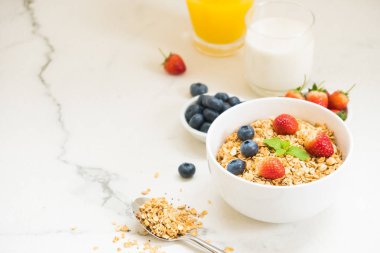 Sağlıklı kahvaltı Granola yaban mersini ve çilek ve siyah kahve, süt ve portakal suyu ile beyaz taş tablo arka planı ayarla