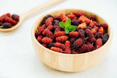 Kırmızı ve siyah dut meyve kase beyaz taş zemin üzerine