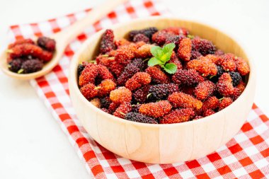 Kırmızı ve siyah dut meyve kase beyaz taş zemin üzerine