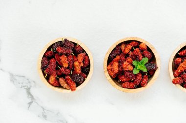Kırmızı ve siyah dut meyve kase beyaz taş zemin üzerine
