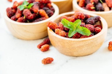 Kırmızı ve siyah dut meyve kase beyaz taş zemin üzerine