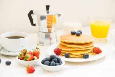 Sağlıklı kahvaltı kümesiyle gözleme ve Granola yaban mersini ve çilek ve siyah kahve, süt ve portakal suyu beyaz taş masa arka plan
