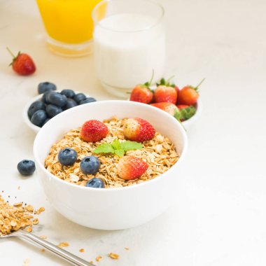 Sağlıklı kahvaltı Granola yaban mersini ve çilek ve siyah kahve, süt ve portakal suyu ile beyaz taş tablo arka planı ayarla
