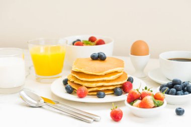 Sağlıklı kahvaltı kümesiyle gözleme ve Granola yaban mersini ve çilek ve siyah kahve, süt ve portakal suyu beyaz taş masa arka plan