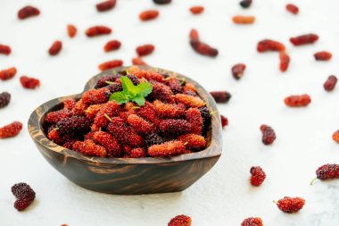 Kırmızı ve siyah dut meyve kase beyaz taş zemin üzerine