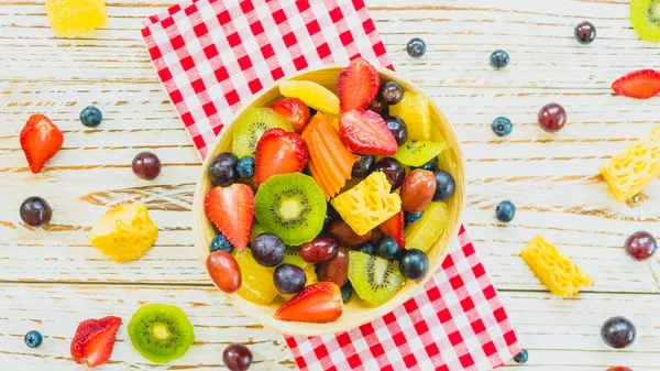 Mixed and assorted fruits with kiwi strawberry grape and other in bowl on wood table - Filter Processing