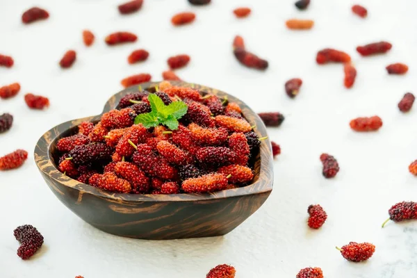 Kırmızı ve siyah dut meyve kase beyaz taş zemin üzerine