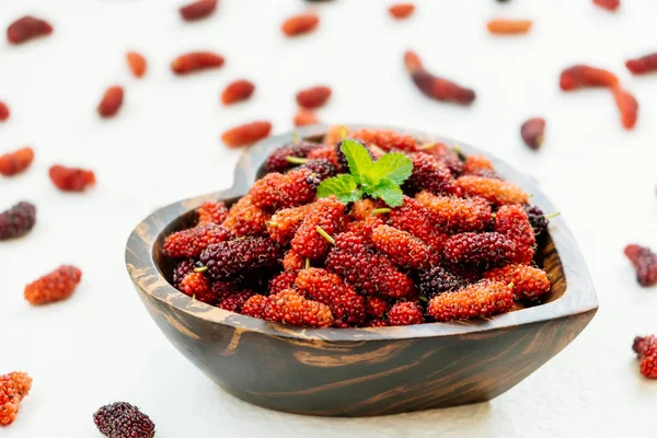 Kırmızı ve siyah dut meyve kase beyaz taş zemin üzerine