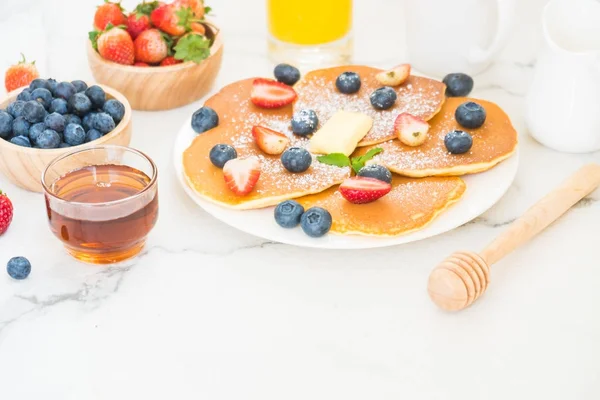 Healthy Breakfast set with Pancake blueberry and strawberry fruits and black coffee , Milk and Orange juice on white stone table background