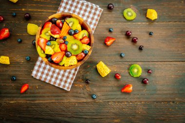 Kivi çilek üzüm ve diğer ahşap masa - filtre işleme üzerinde kase ile karışık ve çeşitli meyve