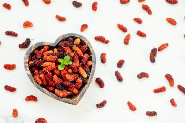 Kırmızı ve siyah dut meyve kase beyaz taş zemin üzerine