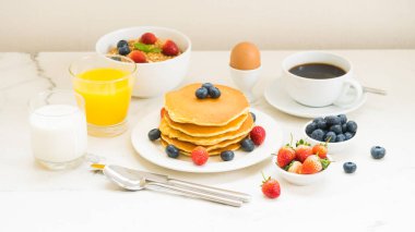 Sağlıklı kahvaltı kümesiyle gözleme ve Granola yaban mersini ve çilek ve siyah kahve, süt ve portakal suyu beyaz taş masa arka plan