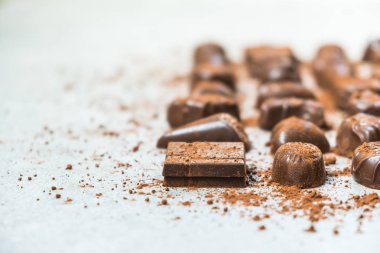Şekerli tatlı koyu çikolata parçaları ve beyaz taş zemin üzerine kakao tozu