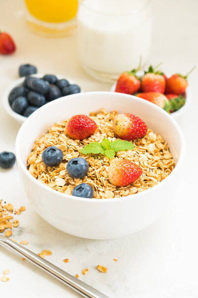 Healthy Breakfast set Granola with blueberry and strawberry and black coffee , Milk and Orange juice on white stone table background
