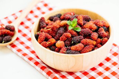 Kırmızı ve siyah dut meyve kase beyaz taş zemin üzerine