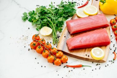 Sebze ve yemek pişirmek için madde ile ahşap kesme tahtası üzerinde ham ton balığı filetosu et
