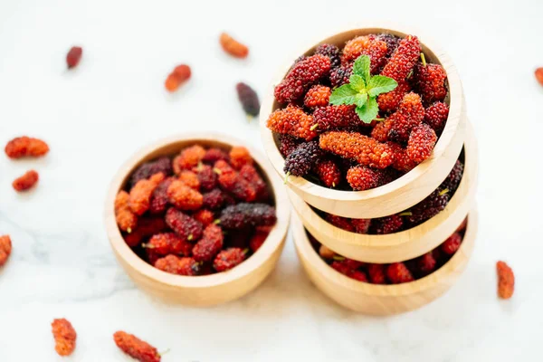 Kırmızı ve siyah dut meyve kase beyaz taş zemin üzerine