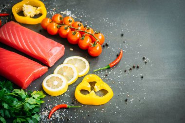 Bitkisel ve siyah taş zemin üzerine yemek için madde ile ahşap kesme tahtası üzerinde ham ton balığı filetosu et