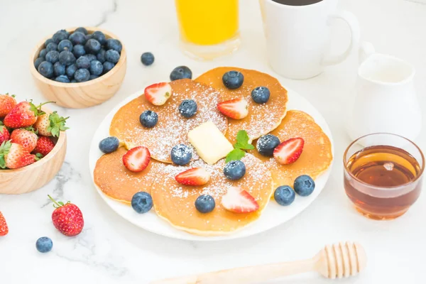 Healthy Breakfast set with Pancake blueberry and strawberry fruits and black coffee , Milk and Orange juice on white stone table background