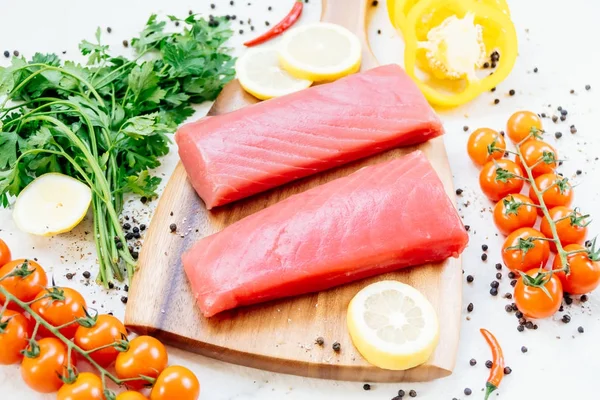 Sebze ve yemek pişirmek için madde ile ahşap kesme tahtası üzerinde ham ton balığı filetosu et