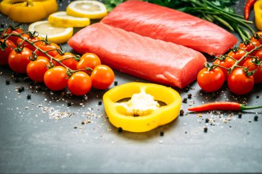 Bitkisel ve siyah taş zemin üzerine yemek için madde ile ahşap kesme tahtası üzerinde ham ton balığı filetosu et