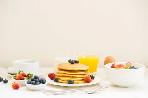 Healthy Breakfast set with Pancake and Granola with blueberry and strawberry and black coffee , Milk and Orange juice on white stone table background