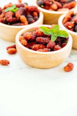 Kırmızı ve siyah dut meyve kase beyaz taş zemin üzerine