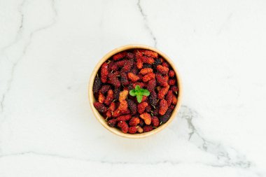 Kırmızı ve siyah dut meyve kase beyaz taş zemin üzerine