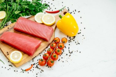 Sebze ve yemek pişirmek için madde ile ahşap kesme tahtası üzerinde ham ton balığı filetosu et