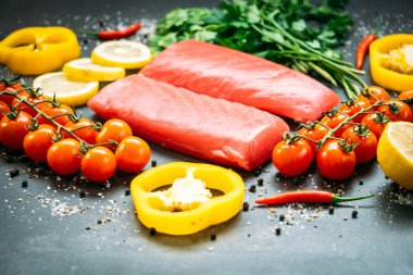 Bitkisel ve siyah taş zemin üzerine yemek için madde ile ahşap kesme tahtası üzerinde ham ton balığı filetosu et