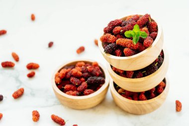 Kırmızı ve siyah dut meyve kase beyaz taş zemin üzerine