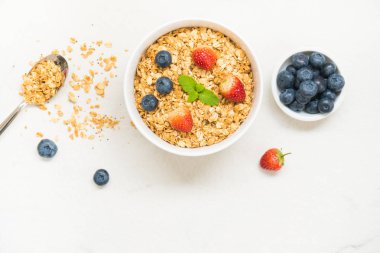 Sağlıklı kahvaltı Granola yaban mersini ve çilek ve siyah kahve, süt ve portakal suyu ile beyaz taş tablo arka planı ayarla