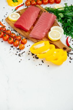 Sebze ve yemek pişirmek için madde ile ahşap kesme tahtası üzerinde ham ton balığı filetosu et