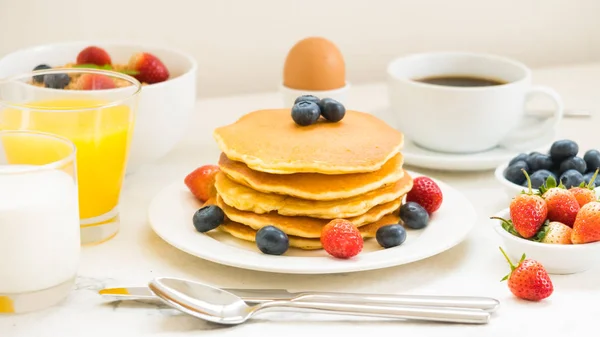 Healthy Breakfast set with Pancake and Granola with blueberry and strawberry and black coffee , Milk and Orange juice on white stone table background