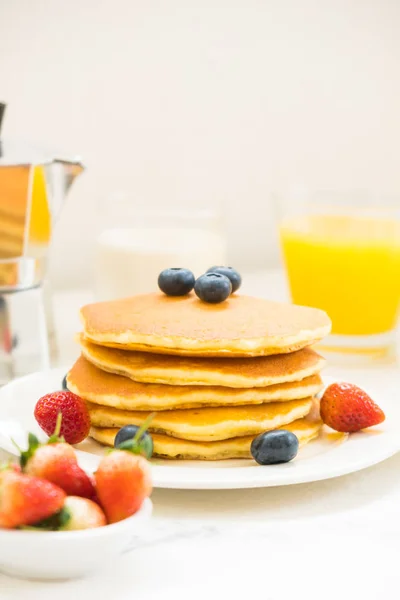 Healthy Breakfast set with Pancake and Granola with blueberry and strawberry and black coffee , Milk and Orange juice on white stone table background